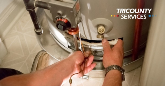 Man shines flashlight on hot water heater.